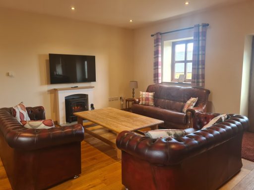 Living room with brown leather sofas, wooden coffee table, and a TV on the wall.