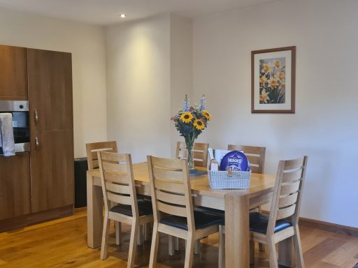 Modern dining area featuring a wooden table, chairs, and a vase of sunflowers.