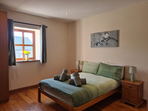 Cosy bedroom with a double bed, wooden furniture, and a window with a scenic view.