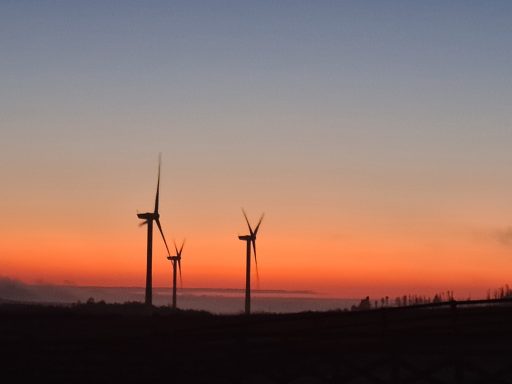 Silhouettes of wind turbines against a colourful sunset sky.