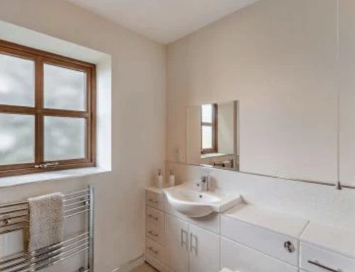 Modern bathroom featuring a sink, mirror, window, and towels on a rack.